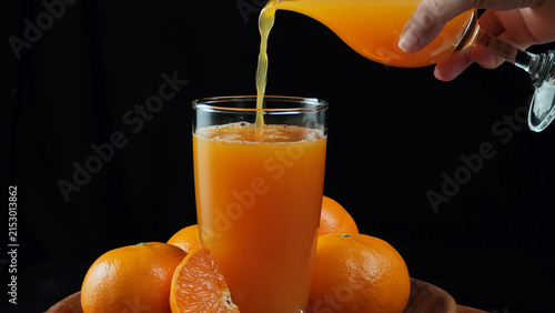 Fresh orange juice pouring into a clear glass container