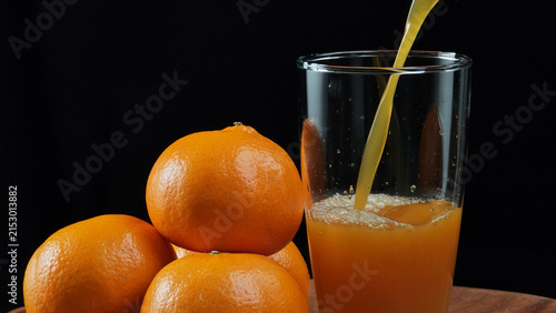 Fresh orange juice pouring into a clear glass container