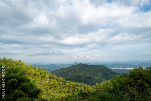 Panoramic View of Lush Green Mountain Range with Bamboo Forest Under Cloudy Sky