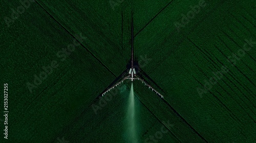 spraying crops evenly across a large green field from above perspective