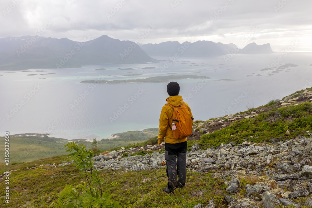 Fototapeta premium Family, hikinh Husfjellet Mountain on Senja Island in northern Norway, bad weather conditions, fog and rain, still enjoying some views over surrounding fjords