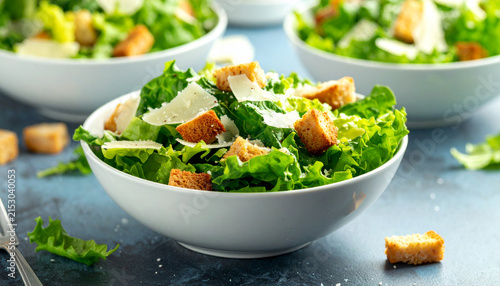 Green lettuce salad with shaved parmesan and golden croutons in a white bowl