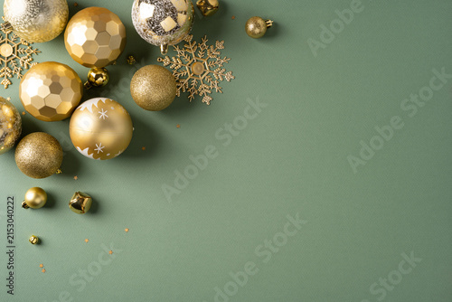 Gold Christmas ornaments and snowflake decorations on green background for New Year greeting
