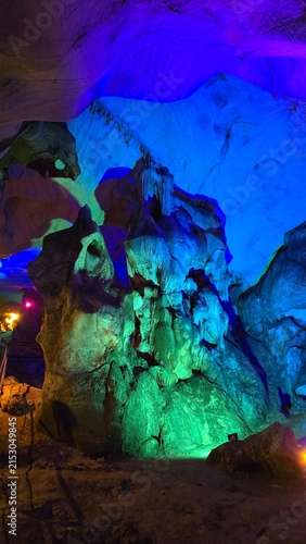 Foto Giant stalagmite formation rising inside a massive cavern under multicolored spo