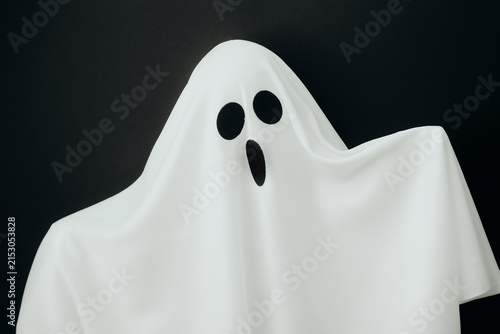 Konstfotografi Surprised white ghost costume with dark holes for eyes on black background