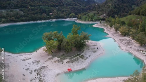 Aerial view of the turquoise waters of Lago di Tenno surrounded by lush green forests and rocky shores in Tenno, Trentino-Alto Adige, Italy.