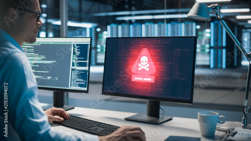 Foto In Data Center Office Male IT Analyst Watches Screens Fill With Virus and Malware Warnings, Popup Showing a Ransomware Attack and Cyber Security Hacking