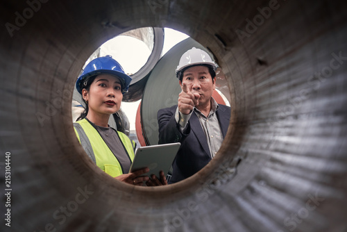 фотографія Technicians Inspecting Metal Pipe in Industrial Factory Setting