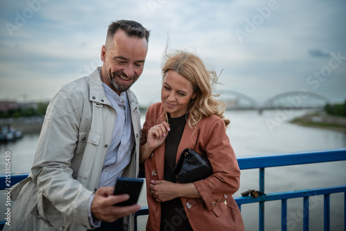 Foto Happy mature couple sharing smartphone content outdoors