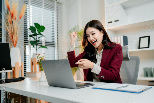 Cuadro en lienzo Happy young asian businesswoman celebrating online business success, feeling exc