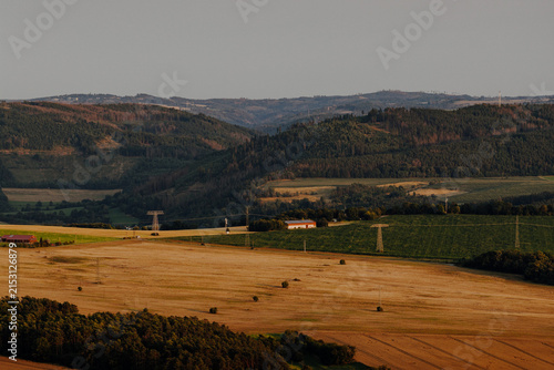 Rural landscape with harvested fields, forested hills and power lines in Germany