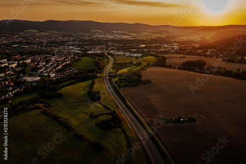 Spectacular aerial sunset landscape with a curving highway and rural town named Saalfeld
