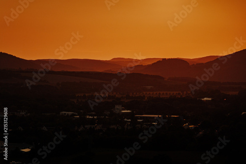 Hazy orange sunset silhouette of rolling hills and a rural town in Thuringia