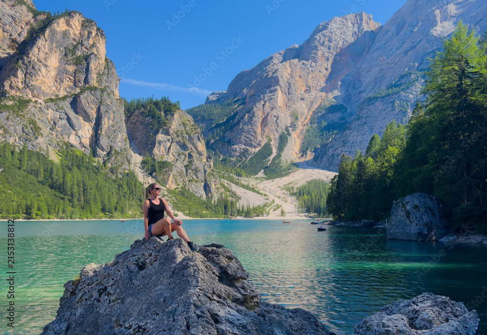Obraz premium Hiking, excited and woman on mountain with lake for adventure, trekking and freedom. Travel, nature and happy person outdoors for wellness, walking and exercise on holiday, journey and vacation