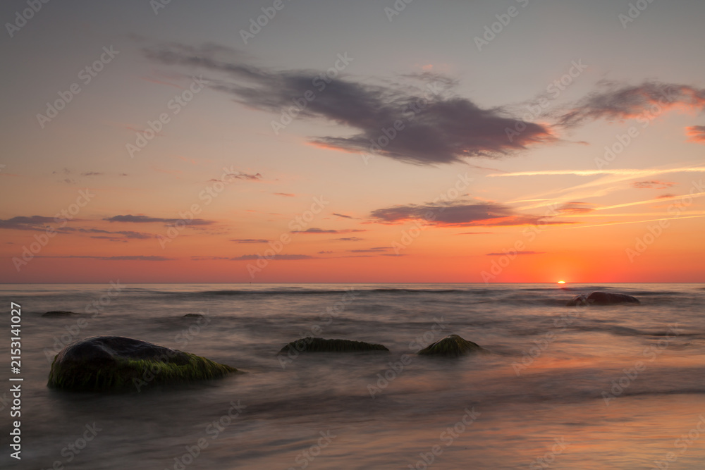 Fototapeta premium Calm sea sunset with rocks and orange sky