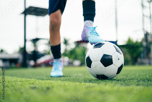 Kid boy leg kicking soccer ball on green grass field action. conceptual metaphor for youth sports training team competition fitness health wellness and active lifestyle