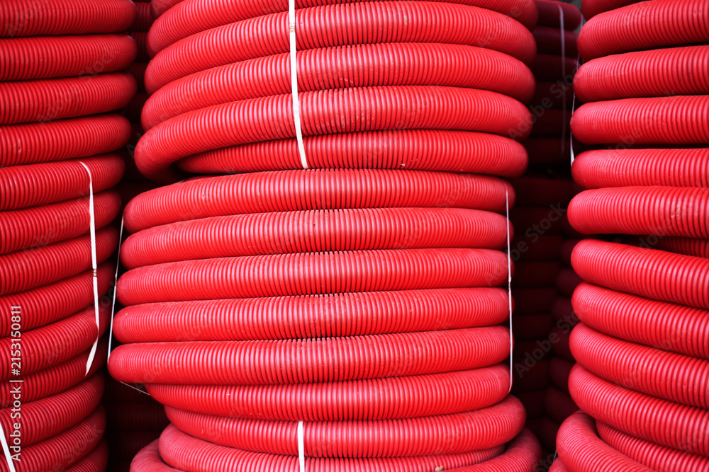 Obraz premium Stacks of red corrugated plastic pipes
