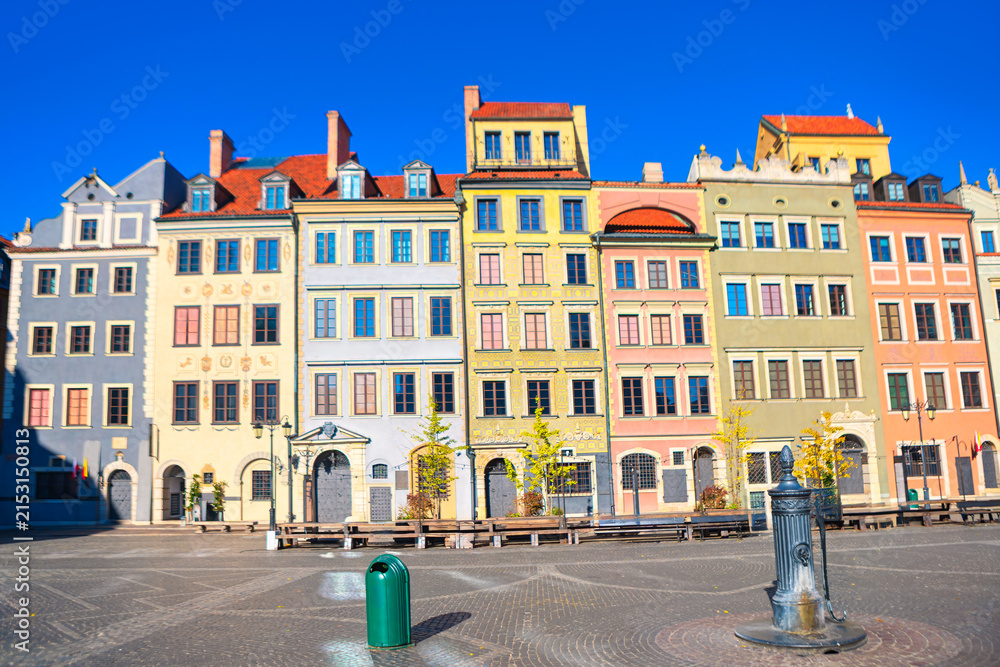 Fototapeta premium Historic Old Town Market Square in Warsaw features row of brightly colored reconstructed townhouses. Cobblestone plaza stretches out in front of the multi-story buildings