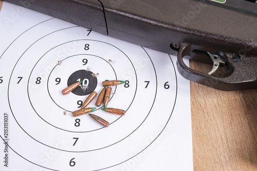 Obraz na płótnie Top View of Airgun Trigger Mechanism with Scattered Bullets on Paper Target