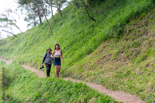 Asian couple hiking through lush green mountain grassland in nature