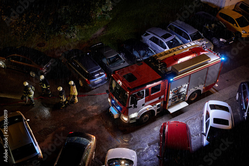 Obraz na płótnie Firefighters professionals and fire truck during nighttime emergency response in heavy rain