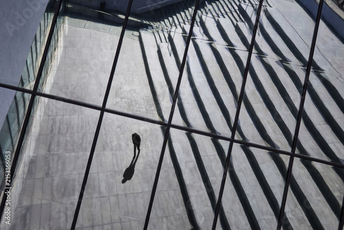 Fotografía Loneliness, mental health, urban isolation concept with solitary person walking through modern city reflection