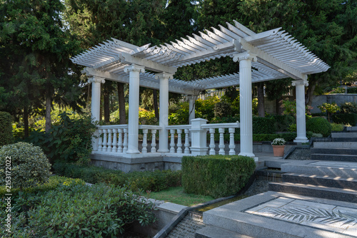 Foto White pergola with classic columns is in Paradise landscape park