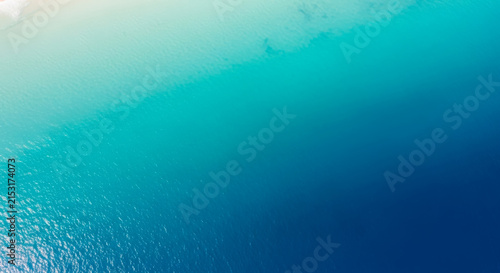 Aerial top view of crystal clear turquoise and deep blue ocean water gradient