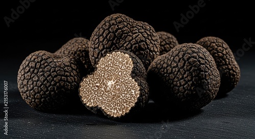 Earthy fresh black truffles rest on a dark slate surface with dramatic side lighting and ample negative space for compositional layouts, gourmet, copy space, fresh