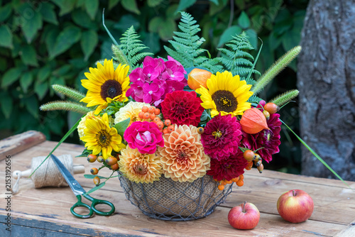 Blumen-Arrangement mit roten und orange Dahlien, Sonnenblumen, Hortensienblüten, Rose, Physalis, Gräsern und Farnblättern im Korb