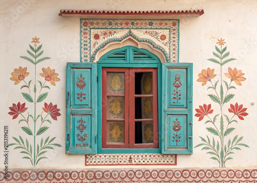 Traditional Indian window with colorful hand-painted floral shutters, carved wooden border, faded turquoise, saffron and crimson colors,