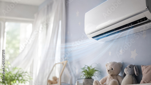 Wall-mounted split air conditioner blowing cool air in a cozy blue children's bedroom with stuffed toys