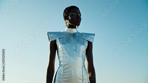 Fashionable woman in silver metallic outfit against sky.