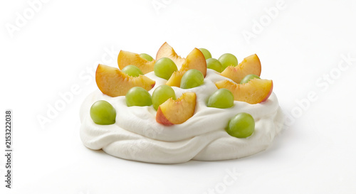 Distant shot of 5 to 10 yellow peach slices and shine muscat grapes nestled on thick white double cream