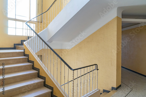 Interior staircase in a residential building with yellow walls and white metal railing