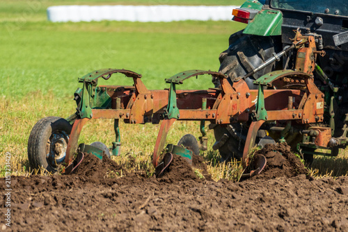 Canvastavla Moldboard plow turning dark soil in a summer agricultural field