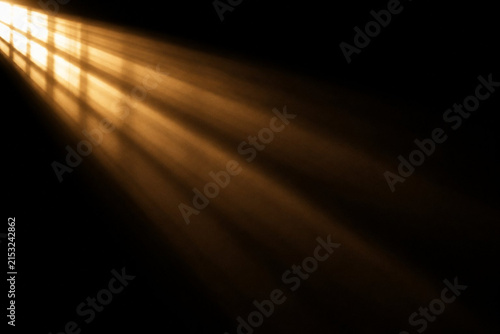 Dramatic light rays from a window in a dark room, creating a moody and atmospheric effect with golden sunbeams piercing through the shadows