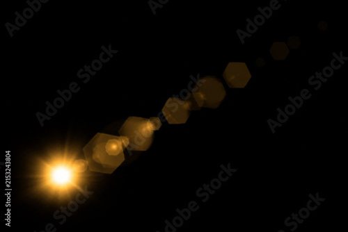 Golden lens flare effect with hexagonal bokeh shapes on black background