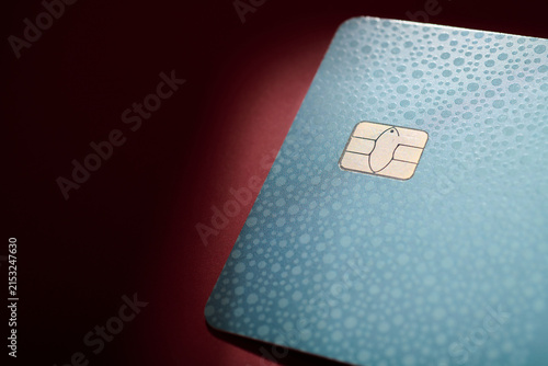 Closeup of a gray debit card with a microchip on a red table