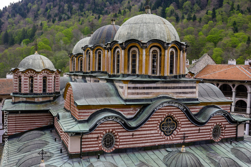 Fotografie The Monastery of Rila, Bulgaria, with its distinctive domes and architecture, set against a backdrop of lush green mountains in spring
