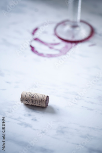 Red wine glass, stains and wine cork on white marble