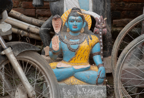 Roadside statue of Lord Shiva watching over parked bicycles in an Indian street