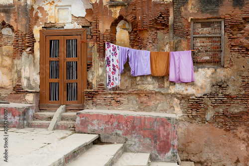Colorful laundry drying outside a weathered old building with a wooden door