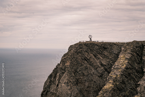 Photography Wide horizon shot of the iconic metal Globe monument standing on the high precipice of North Cape above the endless Arctic Ocean in Norway