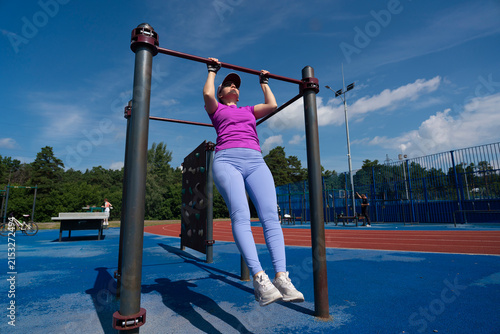 Картината върху платно young female does pull-ups on a crossbar, fitness classes for weight loss