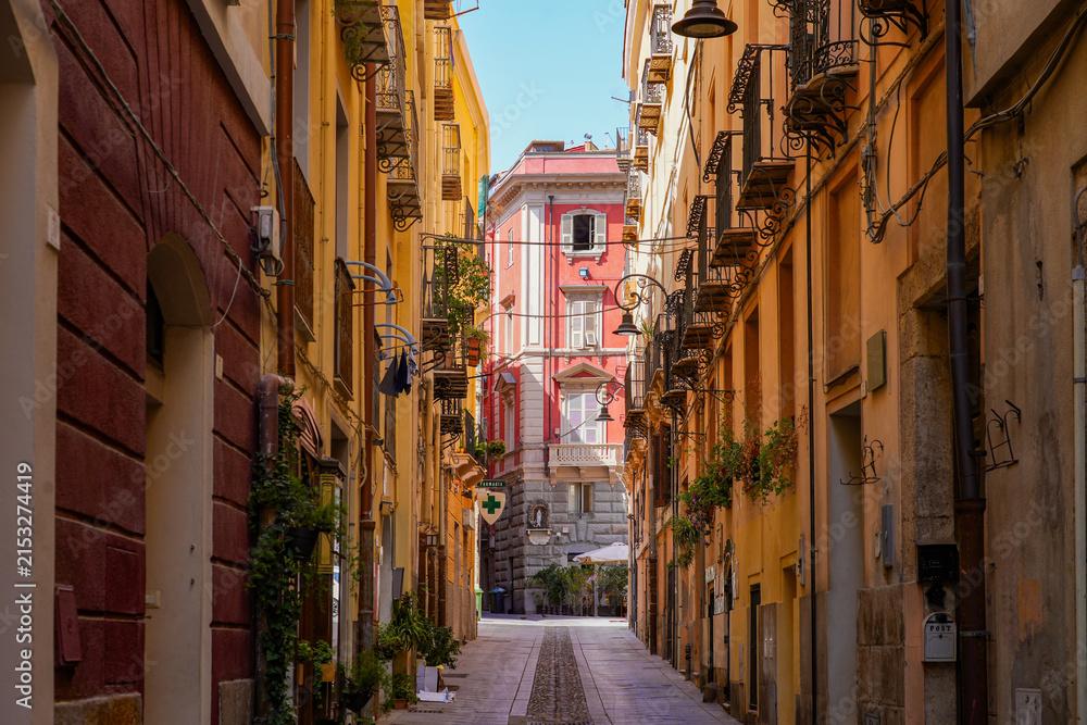 Fototapeta premium Narrow historic street lined with colorful traditional buildings and balconies in Cagliari, Sardinia