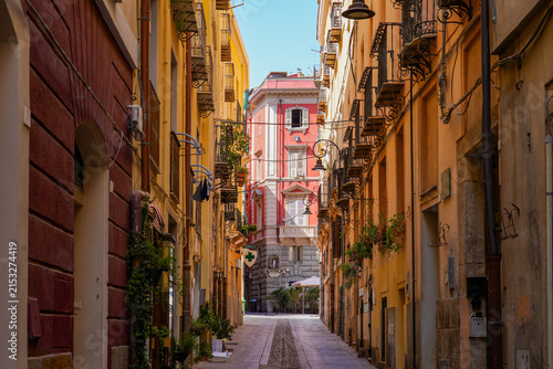 Narrow historic street lined with colorful traditional buildings and balconies in Cagliari, Sardinia