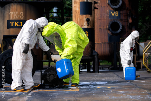 Hazmat workers in protective suits handle a chemical container during hazardous material response training