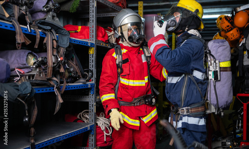 Fotografía Two firefighters assist each other with protective equipment and breathing appar