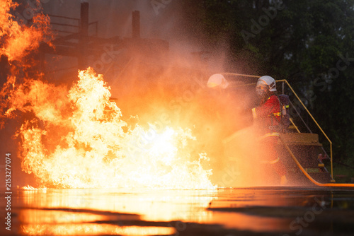 Cuadro en lienzo Firefighters in protective gear spray water to extinguish flames